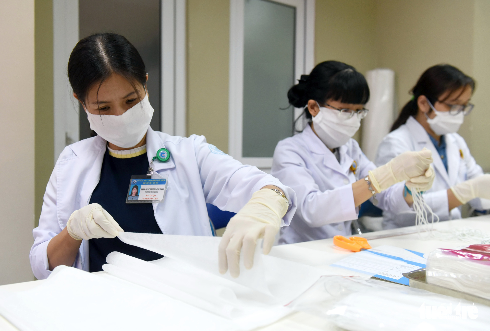 Quach Thi Hoang Anh (L), a doctor at Tu Du Maternity Hospital in Ho Chi Minh City, assists her colleagues in making face masks after her shift, February 13, 2020. Photo: Duyen Phan / Tuoi Tre