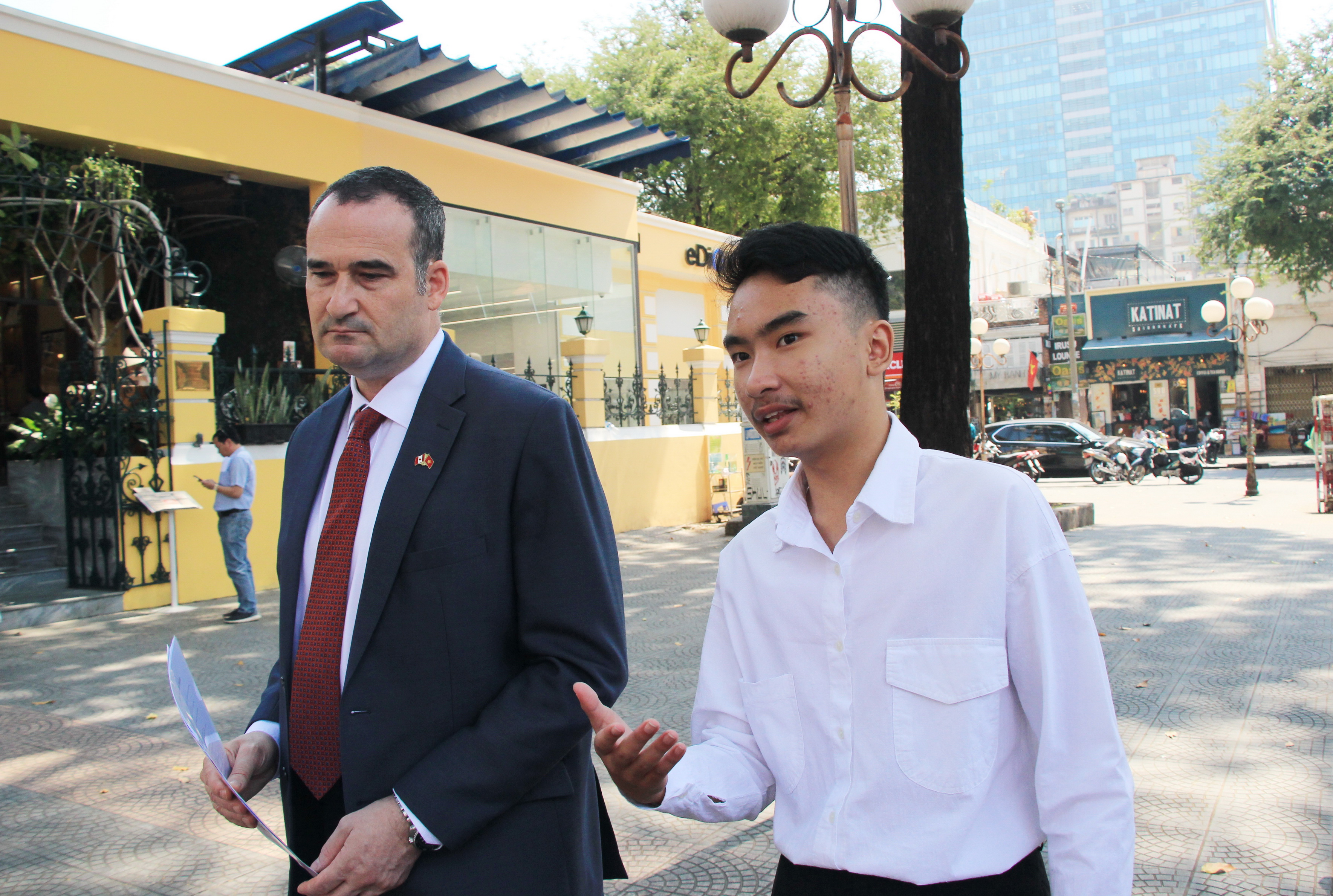 Ninth grader Le Huy Tuan, winner of “Consul General for a Day” competition, talks to Canadian Consul General Kyle Nunas while the two walk on the street in Ho Chi Minh City on February 19, 2020. Photo: Dong Nguyen/Tuoi Tre News