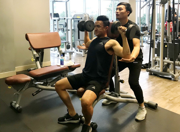 Television anchor Truong Viet Phong (sitting) works out with dumbbells at a gym in Ho Chi Minh City, Vietnam in this provided photo.