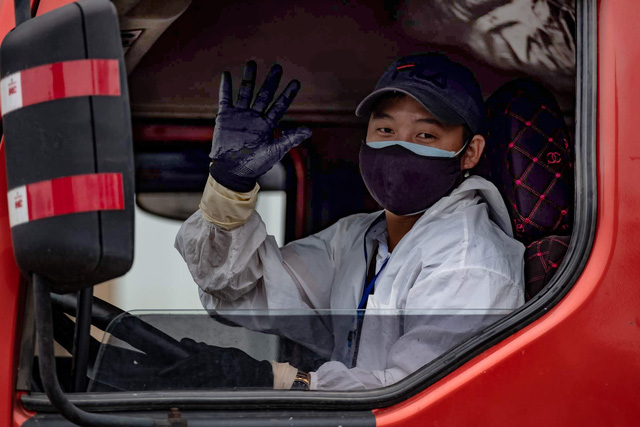 Ly Van Quy, 30, a member of the driver team, waves while doing his job.