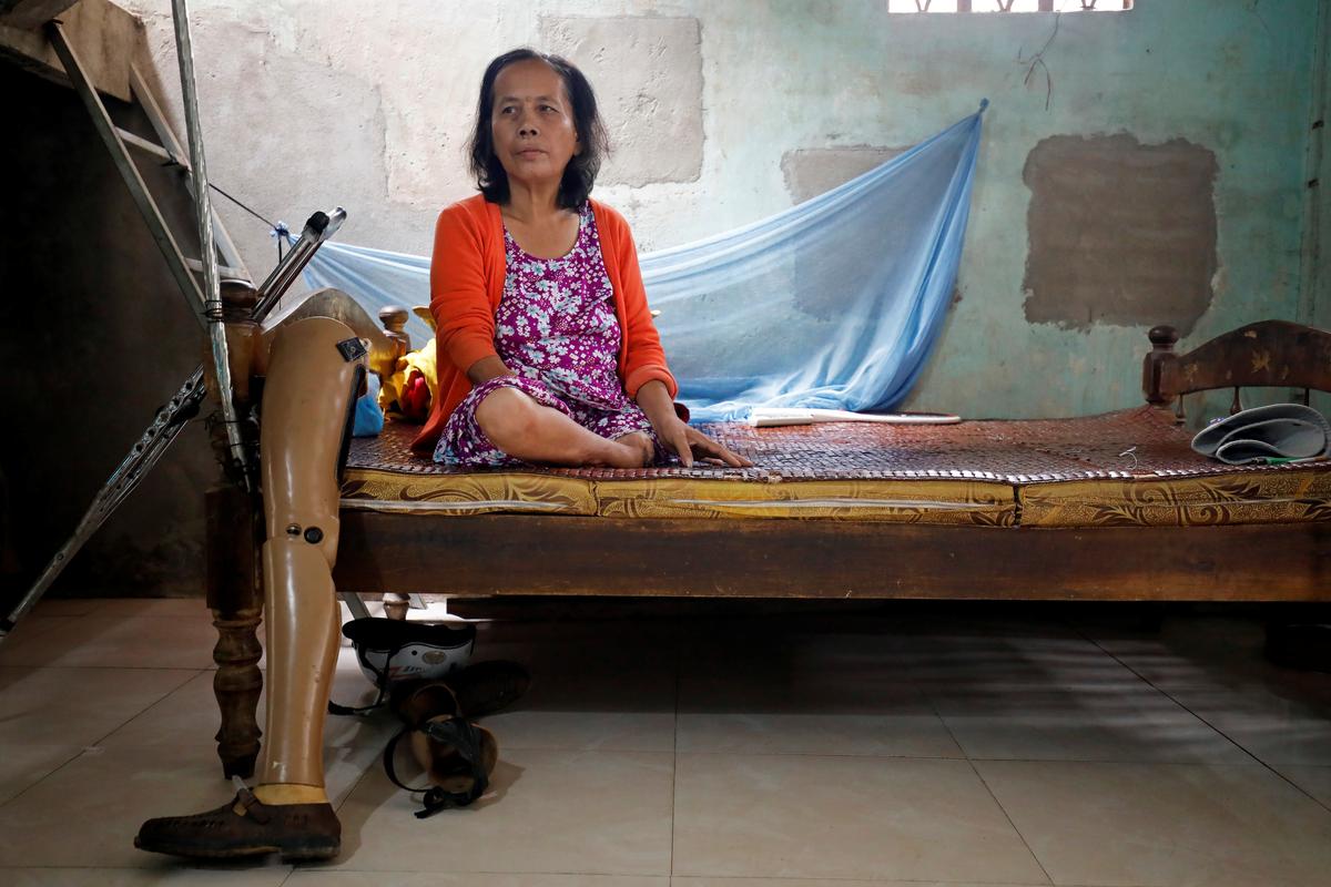 Hoang Thi Hoa, who lost both legs and an arm due to unexploded ordnance (UXO) during the Vietnam War, sits on a bed next to her prosthetics at her house in Quang Tri province, Vietnam March 4, 2020. Picture taken March 4, 2020. Photo: Reuters