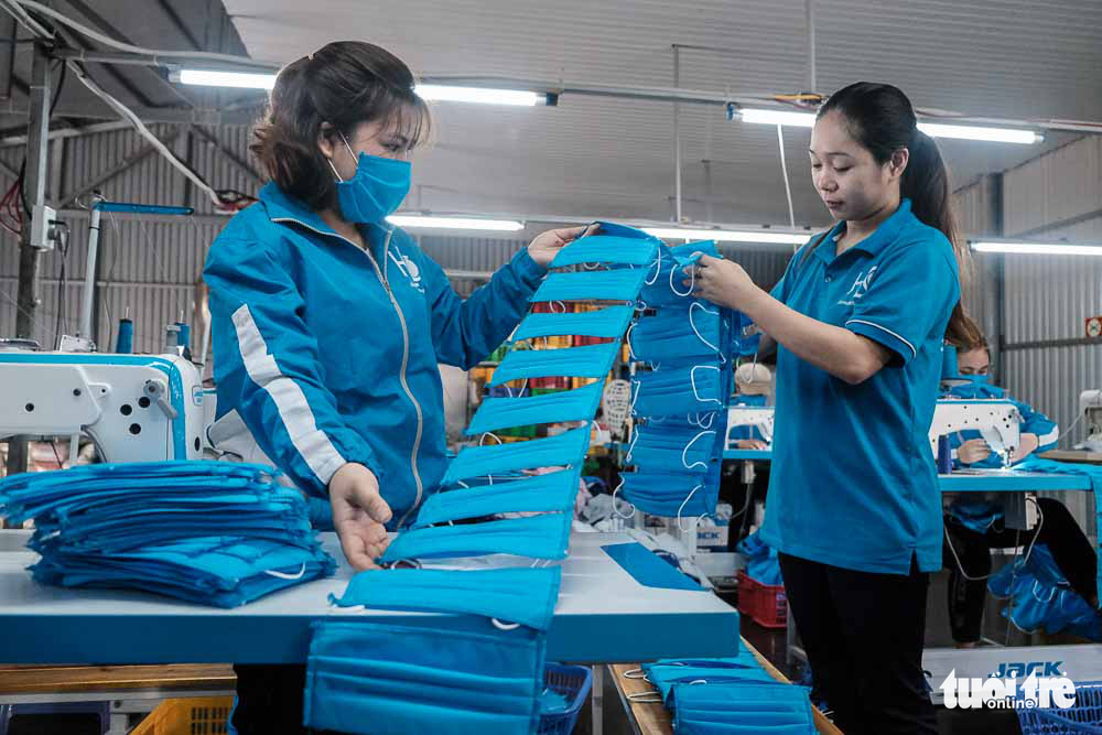 Le Thi Tham (right) inspects the quality of face masks produced at her raincoat factory in Dong Anh District, Hanoi, Vietnam. Photo: Mai Thuong / Tuoi Tre