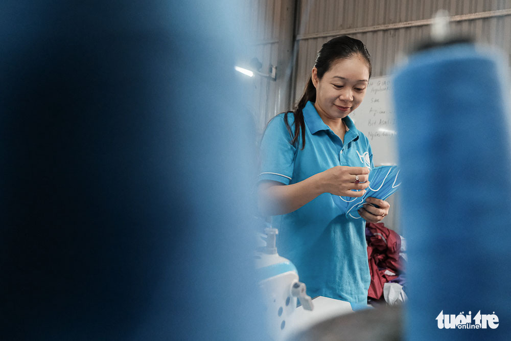Le Thi Tham inspects the quality of face masks produced at her raincoat factory in Dong Anh District, Hanoi, Vietnam. Photo: Mai Thuong / Tuoi Tre