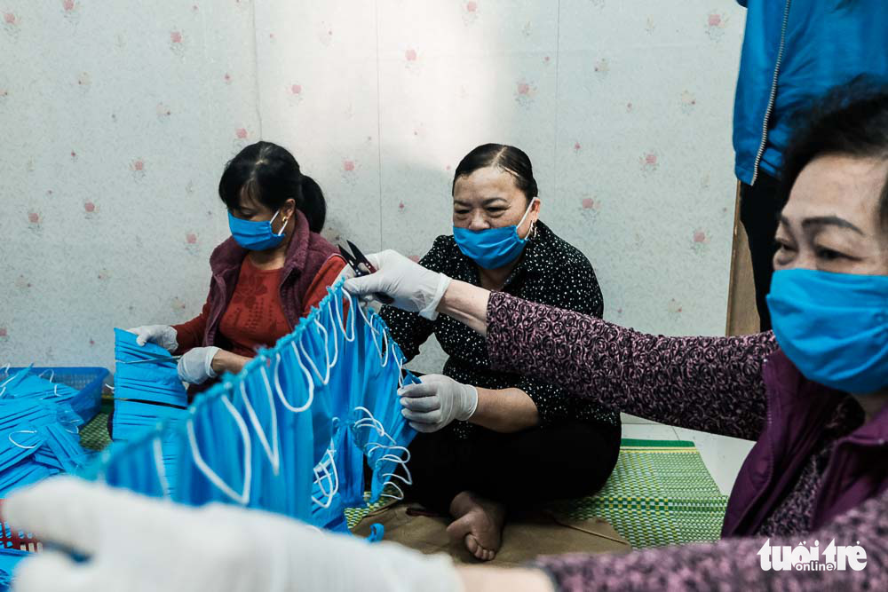 Members of Hai Boi Women’s Union help package finished face masks at a raincoat factory in Dong Anh District, Hanoi, Vietnam. Photo: Mai Thuong / Tuoi Tre