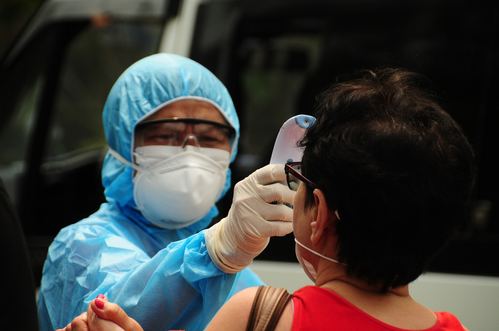 A health worker checks the temperature of a foreign visitor before her quarantine at Hoi An Beach Resort in Hoi An City, Quang Nam Province, Vietnam. Photo: B.D. / Tuoi Tre