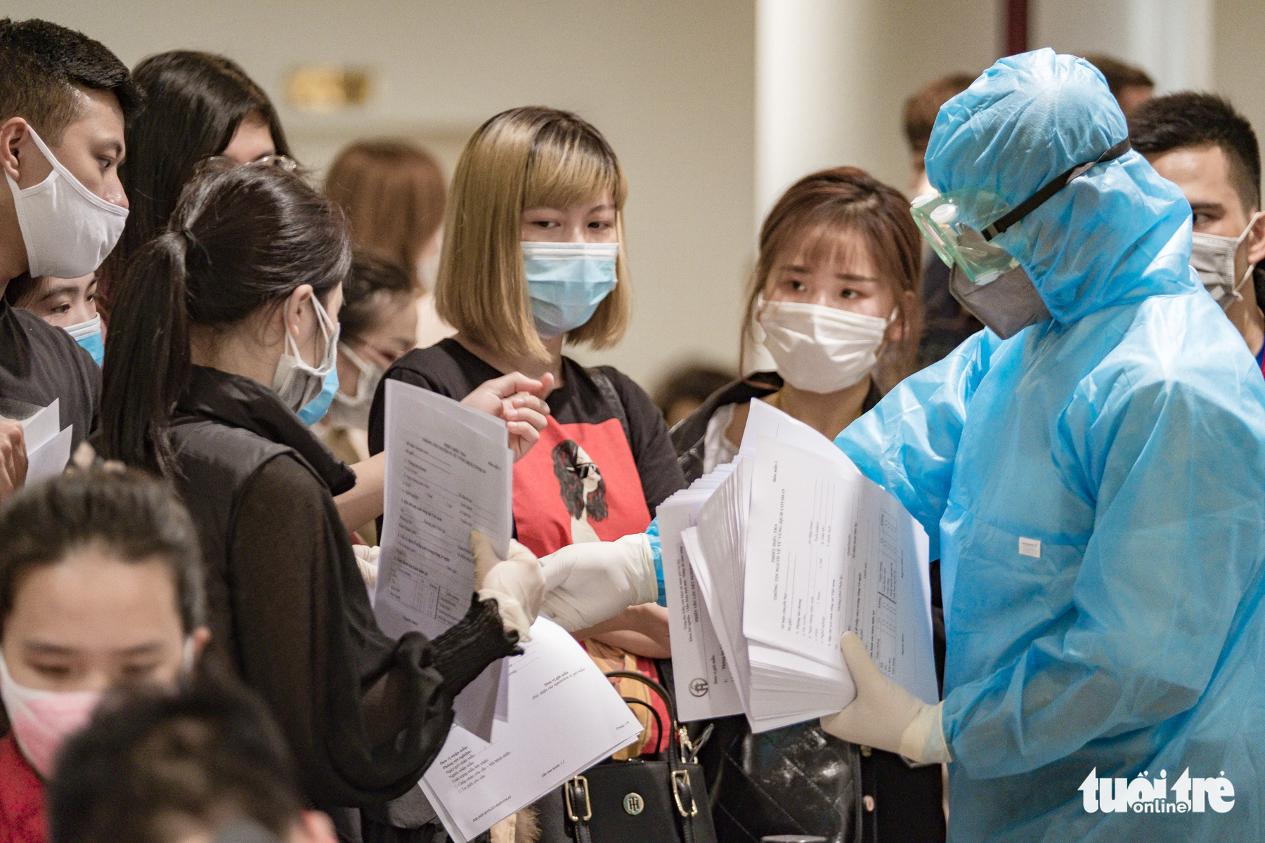 A health worker hands out health declaration forms to passengers arriving at Noi Bai International Airport in Hanoi, Vietnam, March 18, 2020. Photo: Nam Tran / Tuoi Tre