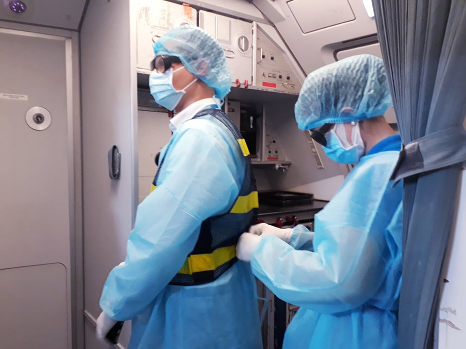 A flight attendant helps her colleague with his protective suit on a charter flight from Cebu Province, the Philippines to Can Tho City, Vietnam,  March 24, 2020. Photo: Khuong Xuan / Tuoi Tre