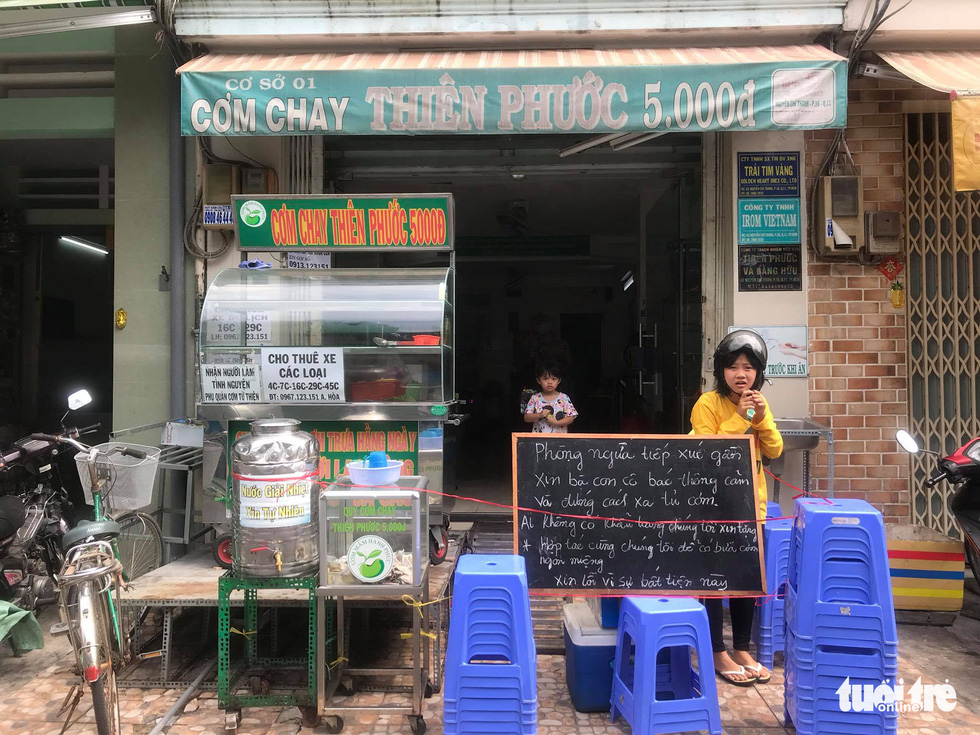 A chalkboard sign reminding customers to practice social distancing is seen outside a vegan storefront in Ho Chi Minh City, Vietnam in this supplied photo.