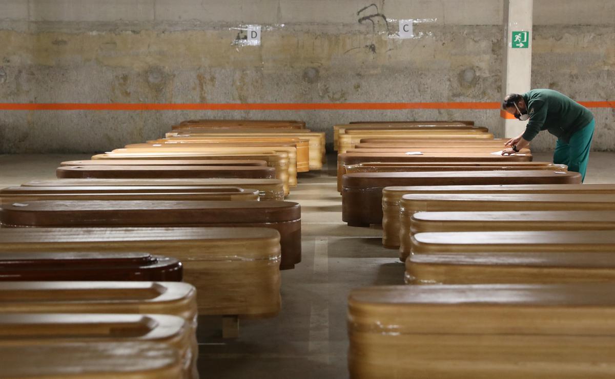 A worker checks coffins, most of them containing the bodies of COVID-19 victims, in the parking of a funeral parlour, during the coronavirus disease (COVID-19) outbreak, in Barcelona, Spain April 2, 2020. Photo: Reuters