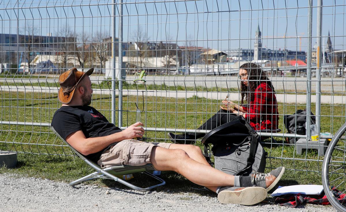 A man and a woman talk through fences set up by Swiss and German authorities on the German-Swiss border as a protection measure due to the spread of the coronavirus disease (COVID-19), in a park on the banks of Lake Constance in Kreuzlingen, Switzerland April 5, 2020. Photo: Reuters