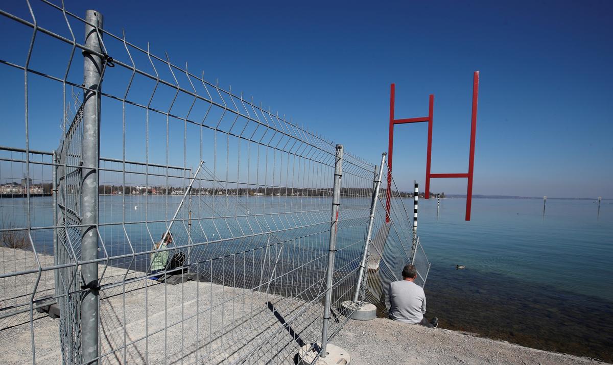 People sit on both sides of fences set up by Swiss and German authorities on the German-Swiss border as a protection measure due to the spread of the coronavirus disease (COVID-19), in an park on the banks of Lake Constance in Kreuzlingen, Switzerland April 5, 2020. Photo: Reuters