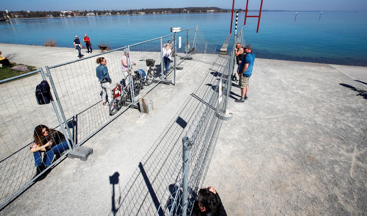 People talk through two fences set up by Swiss and German authorities on the German-Swiss border as a protection measure due to spread of the coronavirus disease (COVID-19), in a park on the banks of Lake Constance in Kreuzlingen, Switzerland April 5, 2020. Photo: Reuters