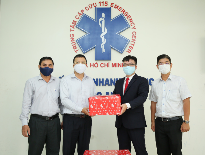 Luu Quoc Khang, Director of VUS's School Services, offers a mask to Dr. Nguyen Duy Long, Director of 115 Emergency Center.