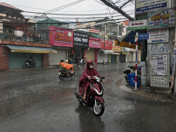 People ride motorbikes in the rain in Tan Phu District, Ho Chi Minh City, April 9, 2020. Photo: Le Phan / Tuoi Tre