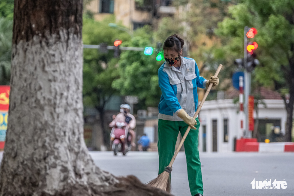 Tran Thi Huong, a sanitation worker from the Hanoi Urban Environment Company, sweeps the street in Hanoi, Vietnam. Photo: Nam Tran / Tuoi Tre