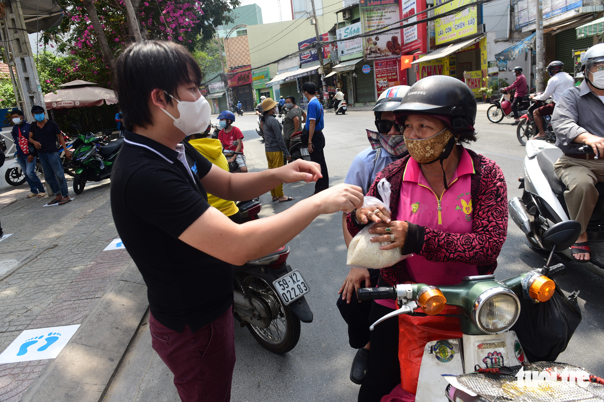 Hoang Tuan Anh (left), owner of a ‘rice ATM’ in Tan Phu District, Ho Chi Minh City, Vietnam hands out plastic bags of rice to the needy. Photo: Quang Dinh / Tuoi Tre