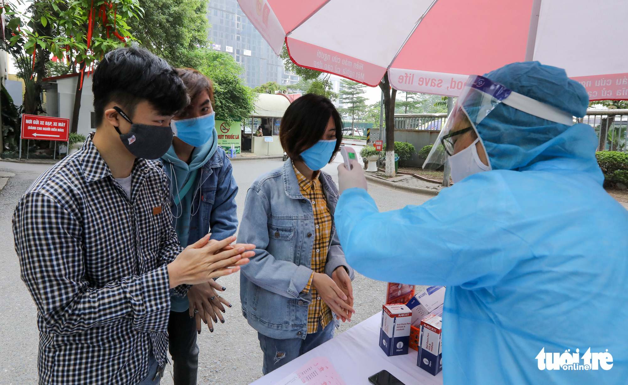 Donors have their body temperature measured and are asked to sanitize their hands before entering the National Institute of Hematology and Blood Transfusion in Hanoi. Photo: Viet Dung / Tuoi Tre