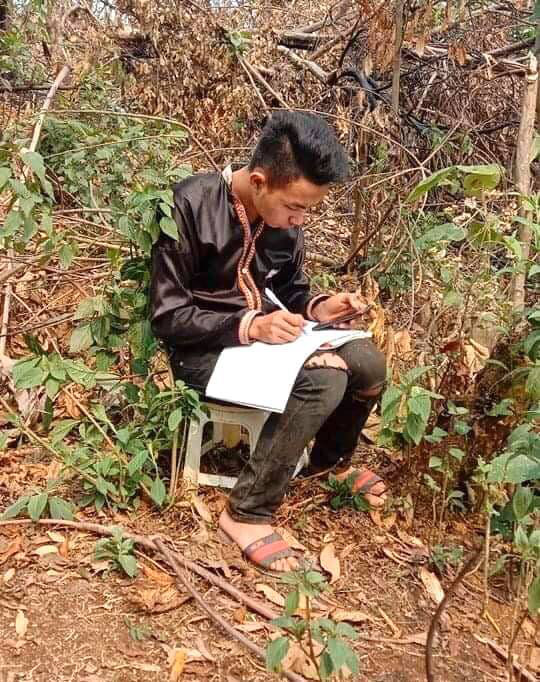 12th grader Sung A Si studies after climbing up a hill next to his house to catch cellular signals.