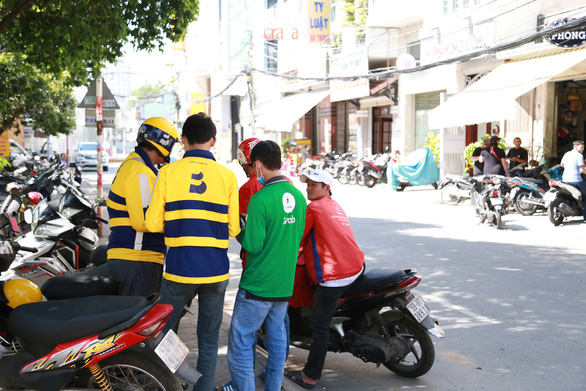 Motorbike riders working for different ride-hail firms gather on the sidewalk of a street in Ho Chi Minh City in this undated photo. Photo: Q.An / Tuoi Tre