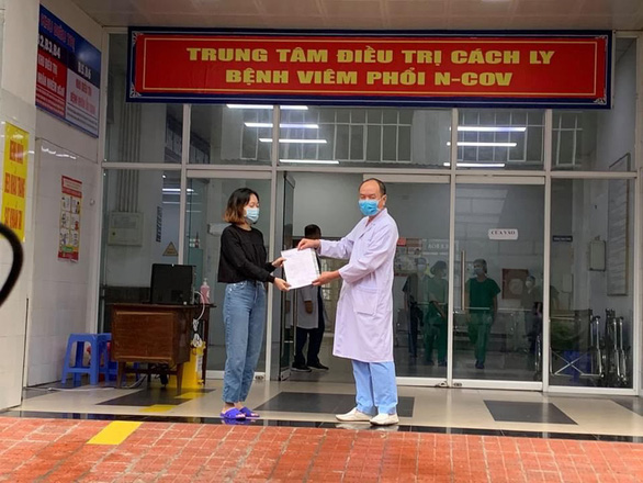 Vietnam’s COVID-19 patient No. 52 (left) receives a hopital discharge certificate in Ha Nam Province in this supplied photo taken on April 16, 2020.