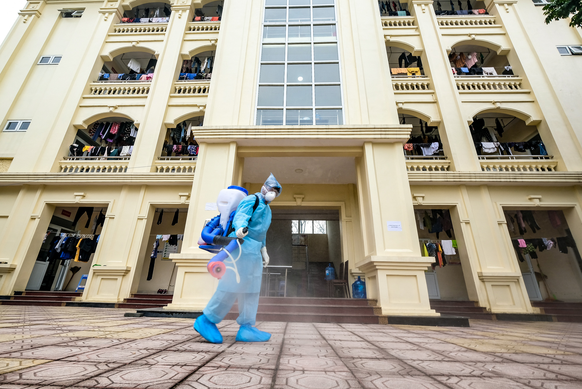A soldier in protective gear disinfects a three-floor building used to isolate people returning from South Korea at a COVID-19 quarantine facility in Hanoi, Vietnam. Photo: Nam Tran / Tuoi Tre