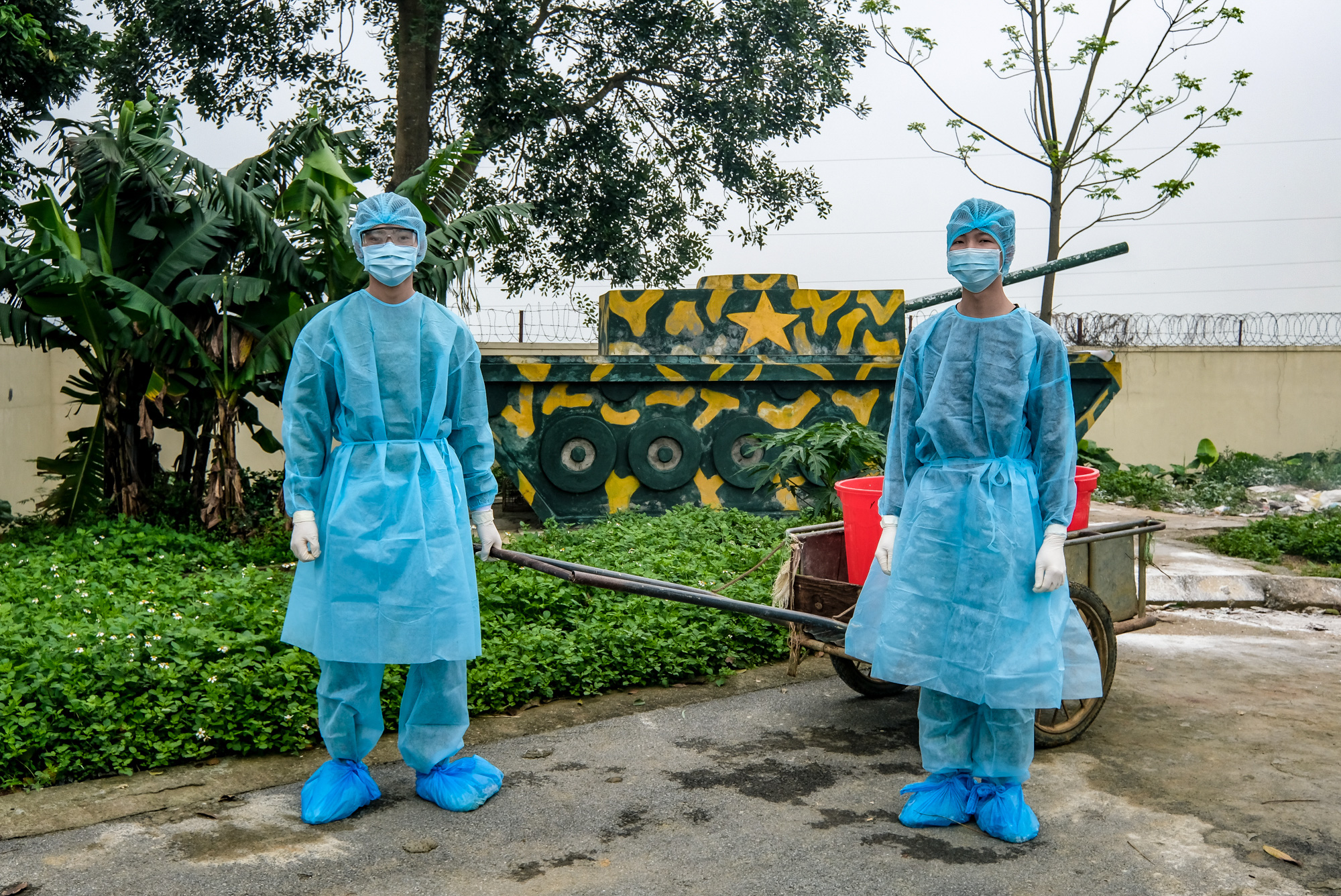 Military personnel in protective gear dispose of garbage at a COVID-19 quarantine facility in Hanoi, Vietnam. Photo: Nam Tran / Tuoi Tre