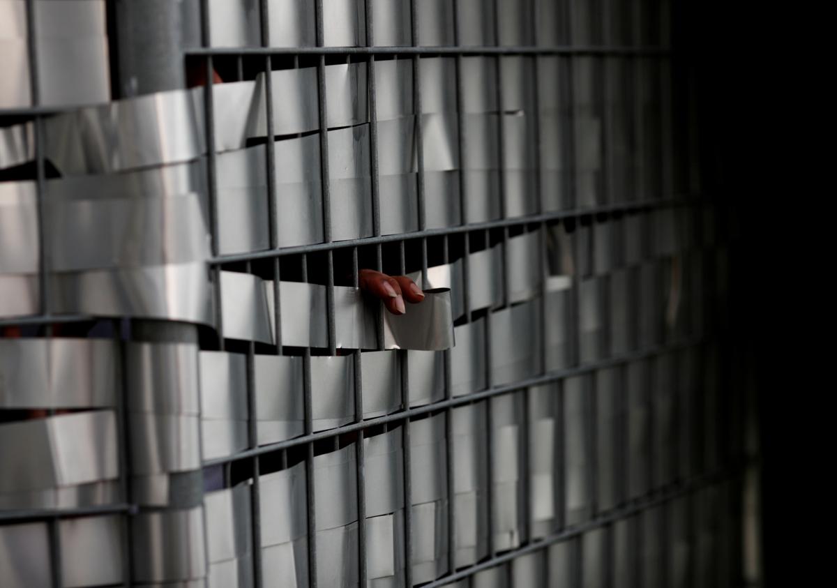 FILE PHOTO: A worker's fingers are pictured as he speaks through a fence with a friend to help with remittance at Punggol S11 workers' dormitory, which was gazetted to be an isolation facility after it became a cluster of coronavirus cases (COVID-19), in Singapore April 6, 2020.  Photo: Reuters