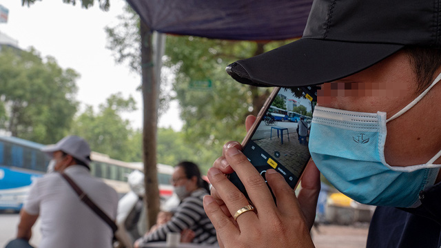 A detective in Vietnam takes photos of his subject while pretending to be on the phone. Photo: V.Tuan / Tuoi Tre