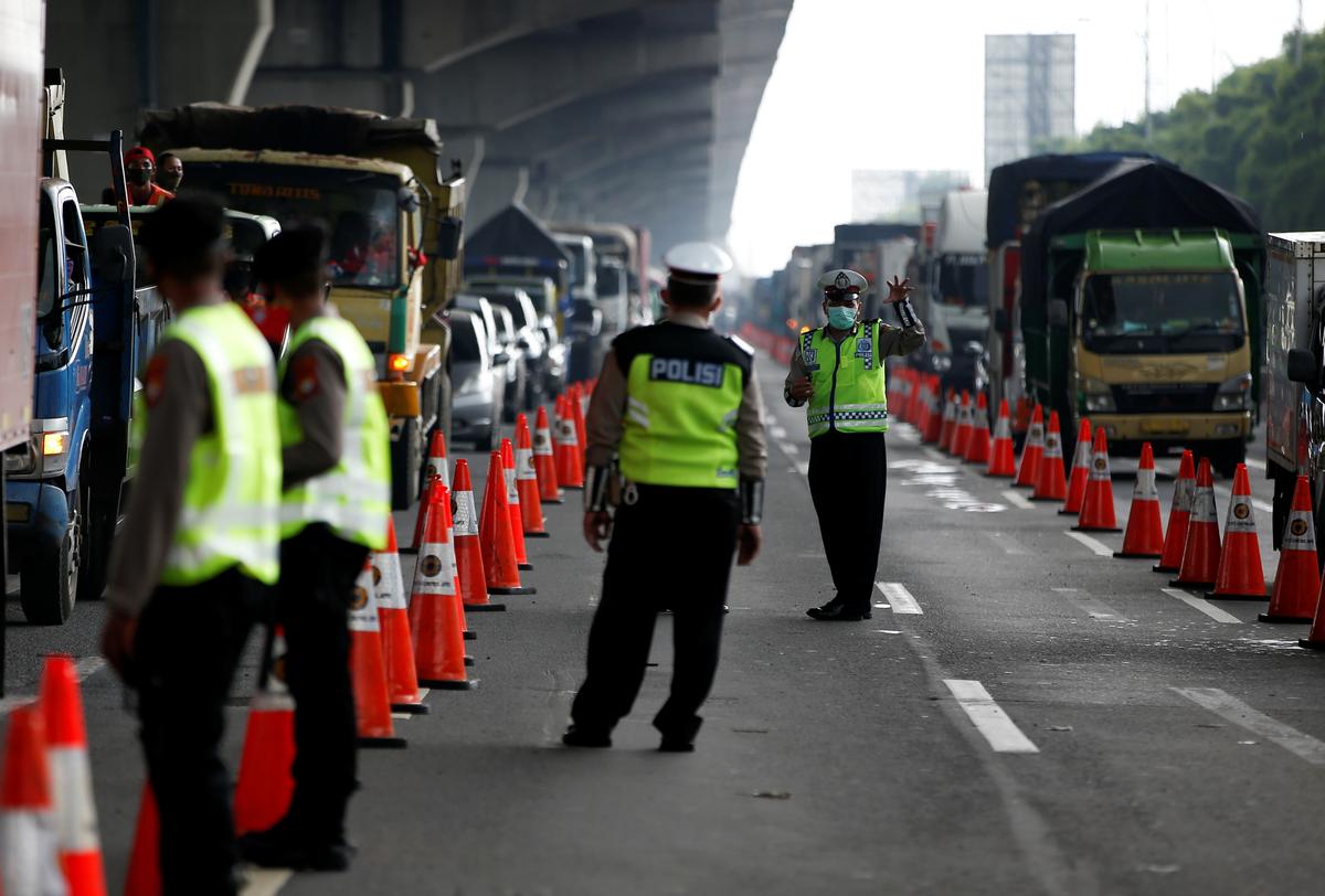 A police officer wearing a protective face mask gestures towards a colleague as they guard a highway checkpoint following the government ban of the Indonesian Muslim traditional homecoming mass exodus to curb the spread of the coronavirus disease (COVID-19) outbreak, in Bekasi, on the outskirts of Jakarta, Indonesia, April 24, 2020. Photo: Reuters