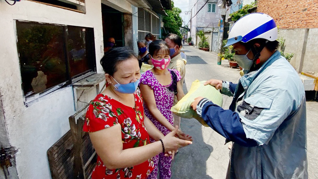 Trieu Van Son (right) gives a bag of rice to a woman in need on Nguyen Son Street in Tan Phu District, Ho Chi Minh City, Vietnam. Photo: Tu Trung / Tuoi Tre