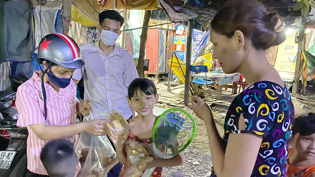 Vietnamese couple Thuy Ai (left) and Nguyen Phan (second left) give away food and presents for the poor and disadvantaged in Binh Hung Commune, Binh Chanh District, Ho Chi Minh City, Vietnam. Photo: Tu Trung / Tuoi Tre