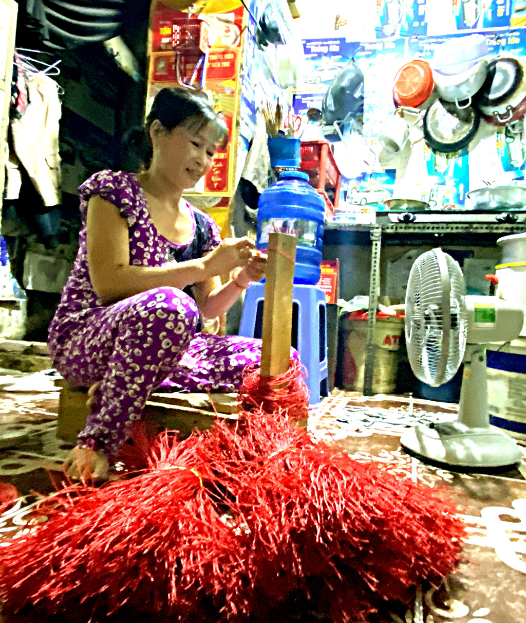 Dang Kim Lu, who has been furloughed from her job as a textile factory worker because of the COVID-19 pandemic, makes strings for a Chinese sausage factory to earn money. Photo: Tu Trung / Tuoi Tre