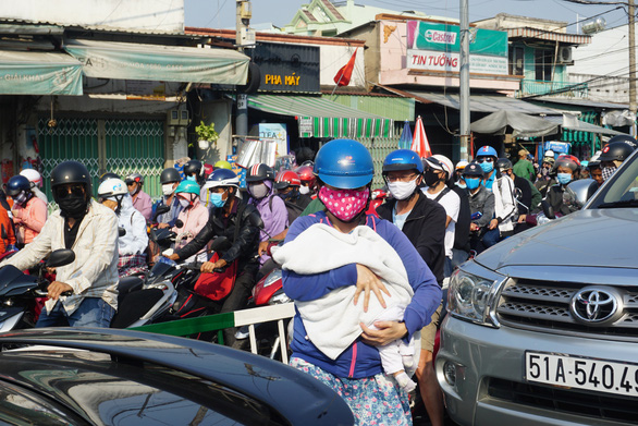 A woman holds her baby walking out of a congestion on Nguyen Thi Dinh Street leading to Cat Lai Ferry in District 2, Ho Chi Minh City, April 30, 2020. Photo: Duc Phu / Tuoi Tre