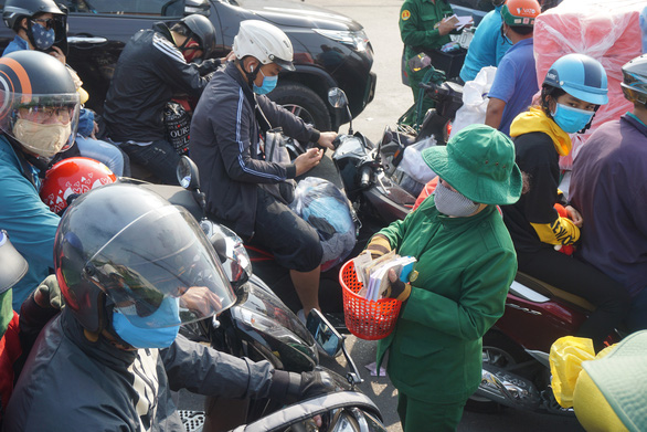 A ticket attendant is surrounded by vehicles dozens meters away from the entrance to Cat Lai Ferry in District 2, Ho Chi Minh City, April 30, 2020. Photo: Duc Phu / Tuoi Tre