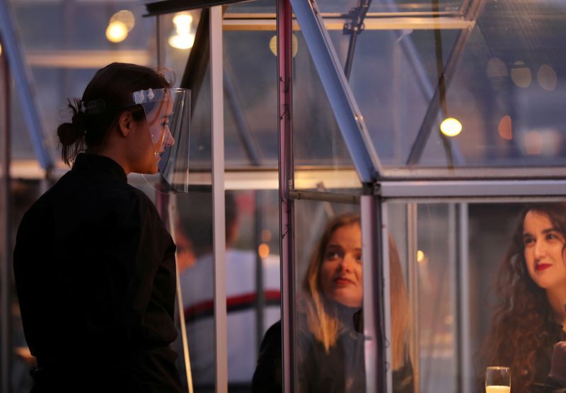 An attendant wearing a clear face shield communicates with customers at a restaurant where 'quarantine greenhouses' being tested in Amsterdam. Photo: Reuters