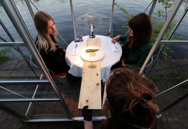 People have meals served on a wooden plank inside a 'quarantine greenhouse' being tested at a restaurant in Amsterdam. Photo: Reuters