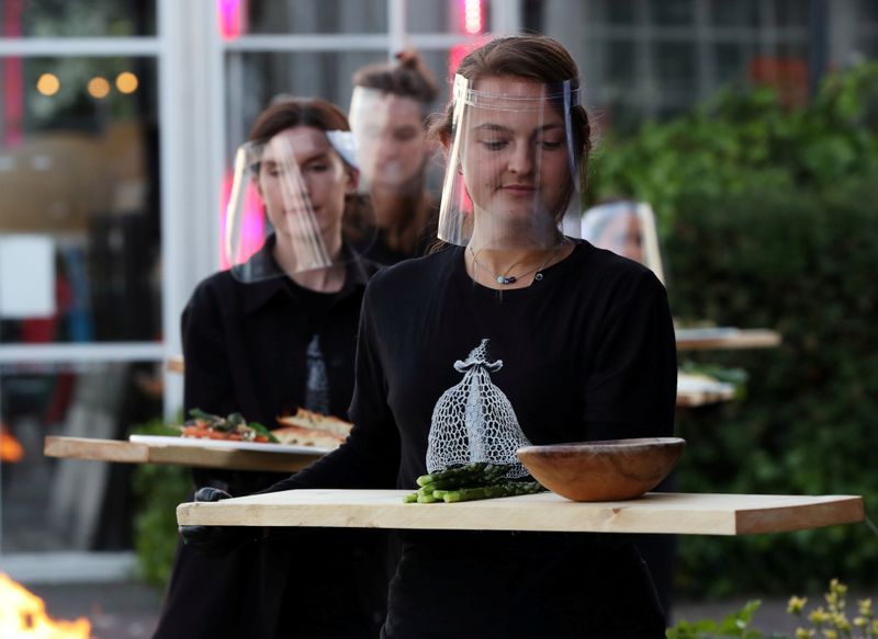 Attendants serve meals on wooden planks at a restaurant where 'quarantine greenhouses' being tested  in Amsterdam. Photo: Reuters