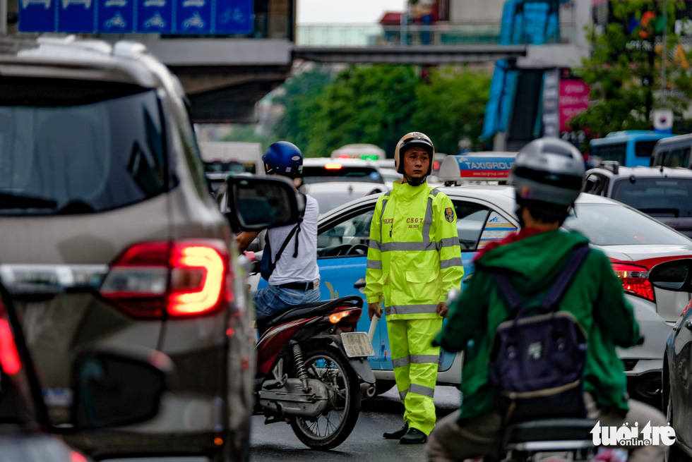 A traffic police officer monitors traffic in the middle of congestion on Nguyen Trai Street, Hanoi, after a sudden downpour in the morning of May 12, 2020. Photo: Nam Tran / Tuoi Tre