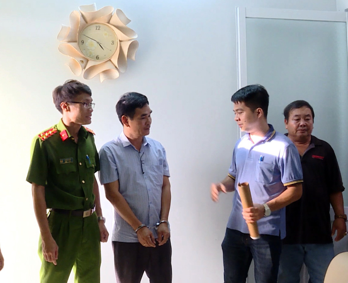 Police officers search the workplace of Le Van Ly (second left) at an office of the Nhan Dao & Doi Song magazine in Ba Ria-Vung Tau Province, Vietnam after he allegedly posed as a reporter to blackmail a local company leader. Photo: Quynh Giang / Tuoi re