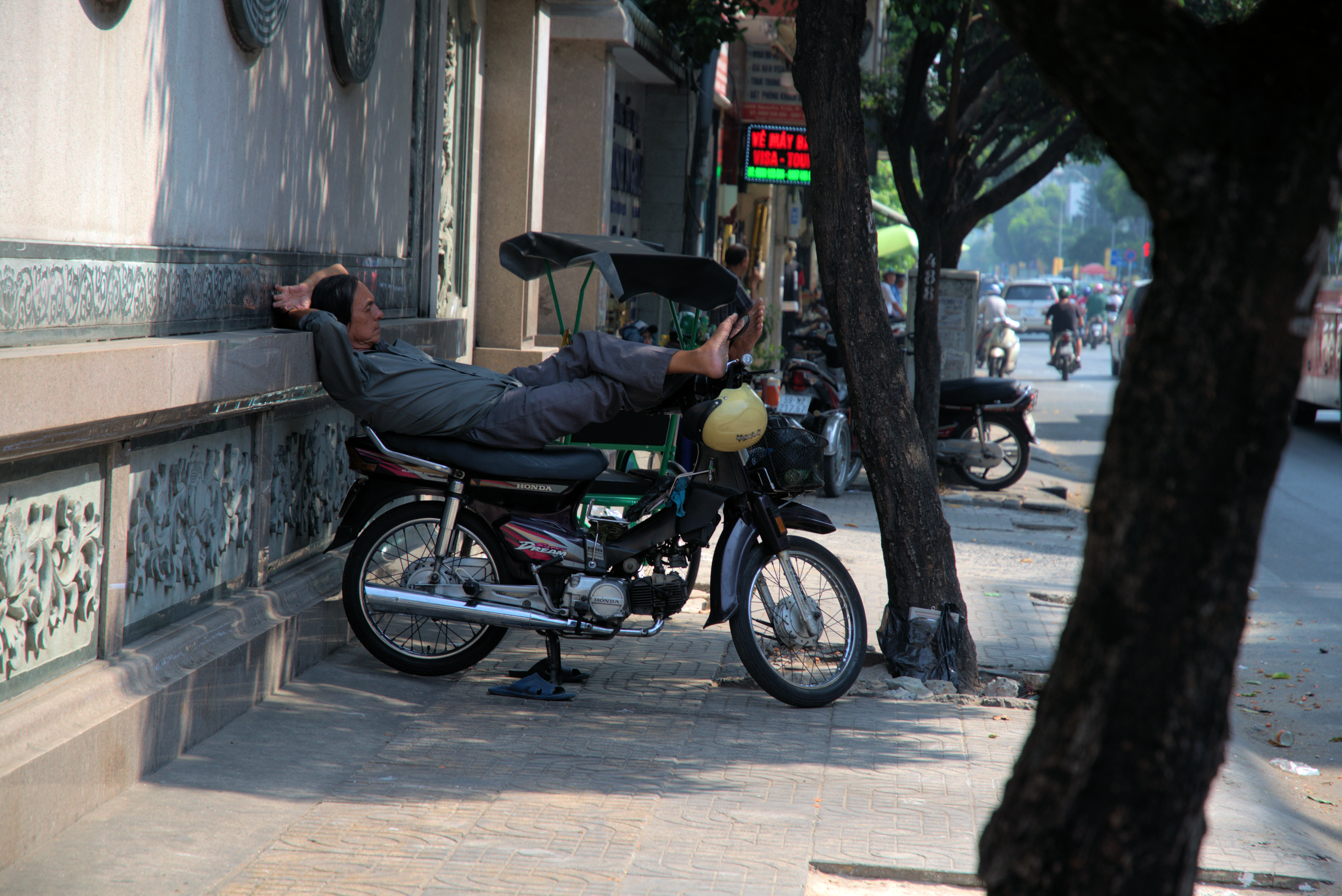 A  xe om (motorbike taxi) driver is seen taking a nap on the sidewalk in the photo captured by Kyle Nunas.