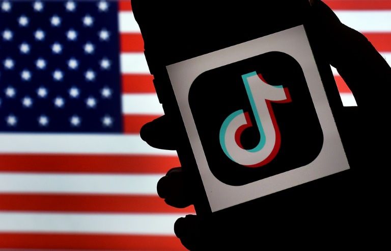 In this photo illustration, the social media application logo, TikTok is displayed on the screen of an iPhone on an American flag background on August 3, 2020 in Arlington, Virginia. Photo: AFP