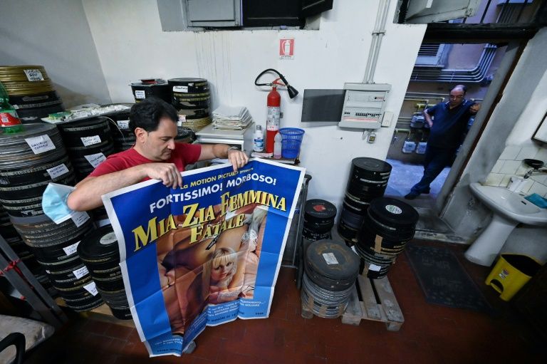 Carlo, an employee of the 'Ambasciatori' (The Ambassadors), Rome's last porn cinema theater, displays a porn film's poster, August 26, 2020. Photo: AFP