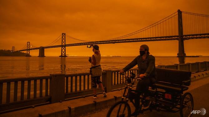 Amy Scott of San Francisco takes in the view from the Embarcadero as smoke from various wildfires burning across Northern California mixes with the marine layer, blanketing San Francisco in darkness and an orange glow. Photo: AFP