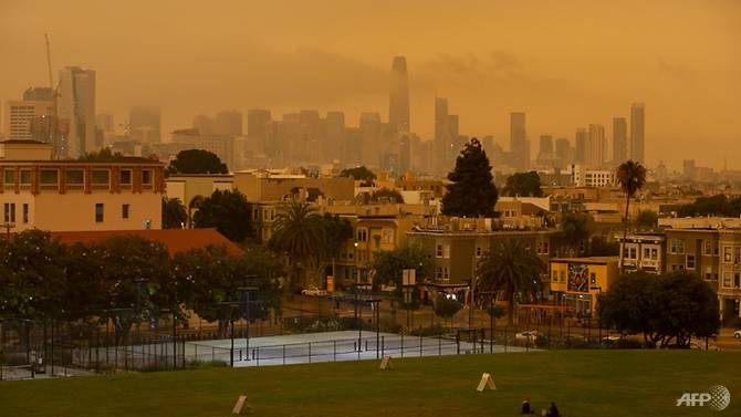 People relax under an orange smoke-filled sky at Dolores Park in San Francisco, California on Sep 9, 2020. Photo: