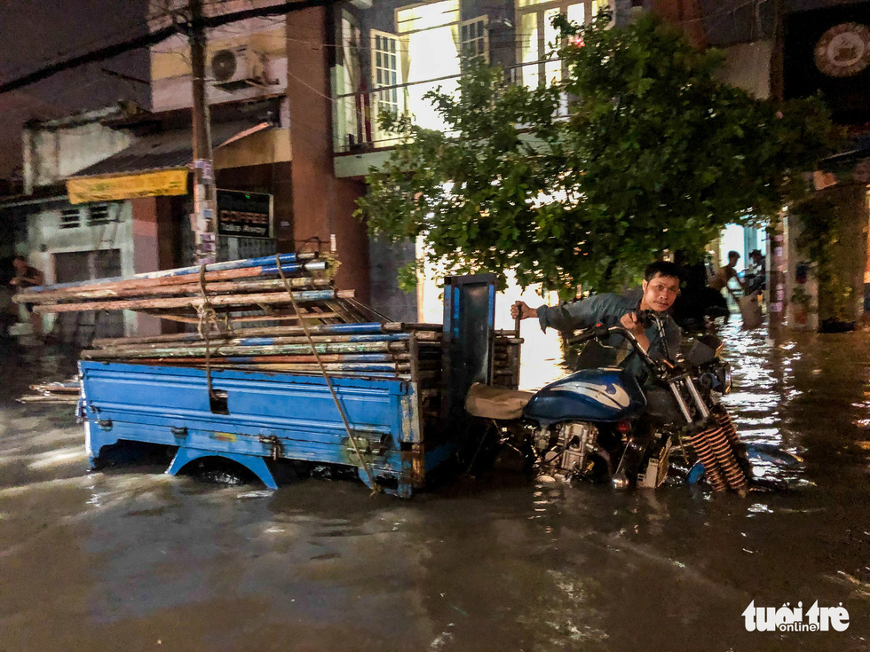 A man walks his vehicle through a flooded street after a heavy rain in Thu Duc District,  Ho Chi Minh City, September 11, 2020. Photo: Chau Tuan / Tuoi Tre