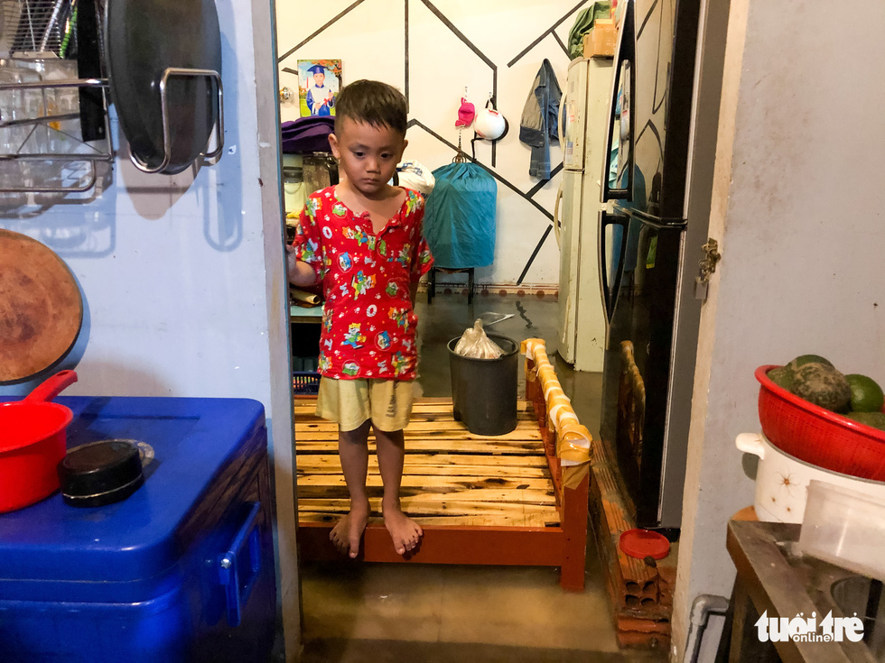 A boy stands on a bed as his house is submerged in rainwater after a heavy rain in Thu Duc District,  Ho Chi Minh City, September 11, 2020. Photo: Chau Tuan / Tuoi Tre