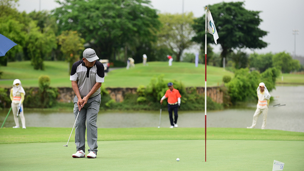 A golfer and a backdrop of other golfers watch his golf ball after hitting it on a golf course in Vietnam. Photo: Quang Dinh / Tuoi Tre