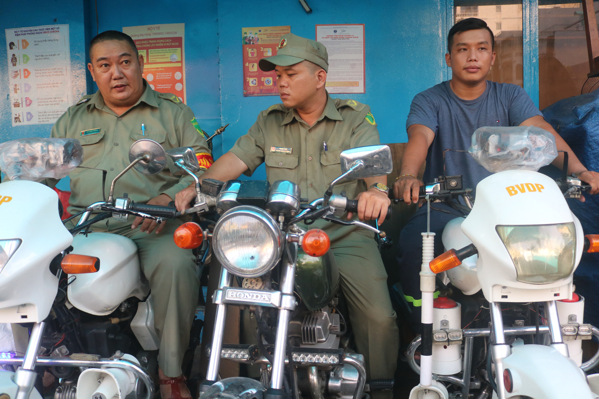 Ly Nhon Thanh (left) sits on his motorcycle next to two coworkers. He bought the motorcycle with his own money to chase robbers. Photo: Thu Hien / Tuoi Tre