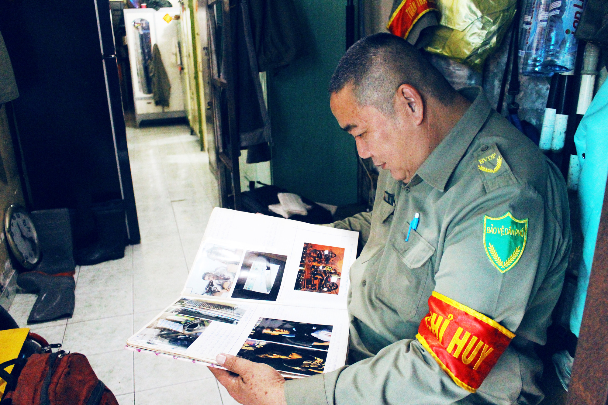 Ly Nhon Thanh looks at a journal where he keeps photos of his past cases of chasing after robbers. Photo: Kim Ut / Tuoi Tre