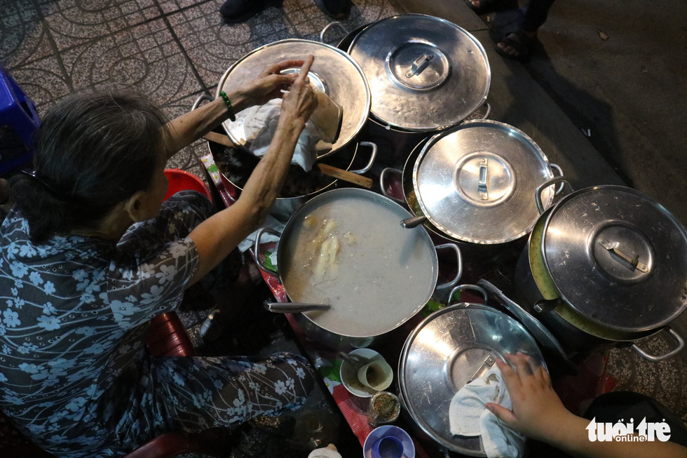 Sau’s stall is made up of a small table serving five pots of 'chè' (a Vietnamese sweet dessert) and a pot of coconut milk surrounded by small plastic stools. Photo: Ngoc Phuong / Tuoi Tre